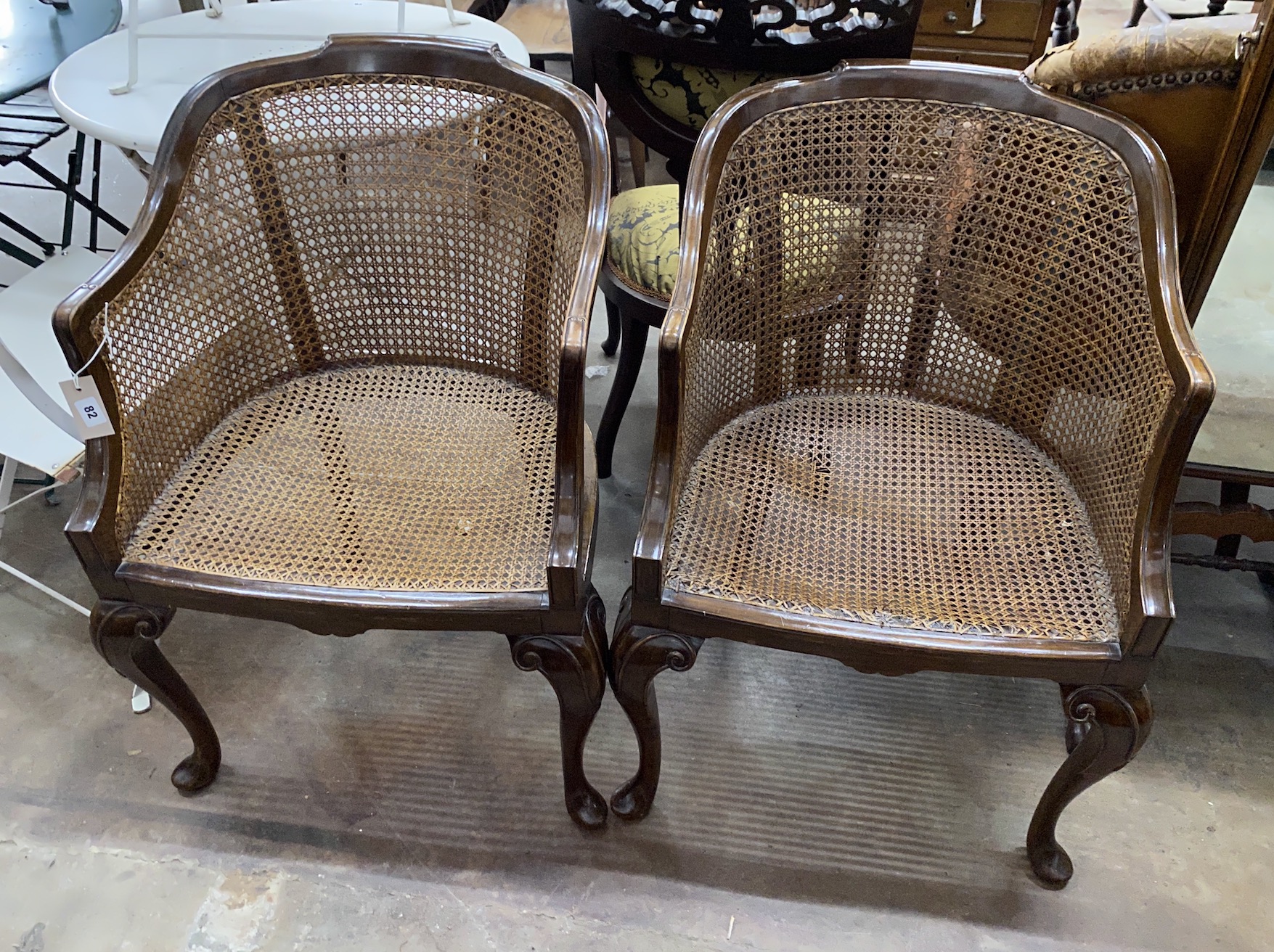 A pair of Queen Anne revival walnut cane seat tub framed bergere armchairs, width 55cm, depth 45cm, height 86cm